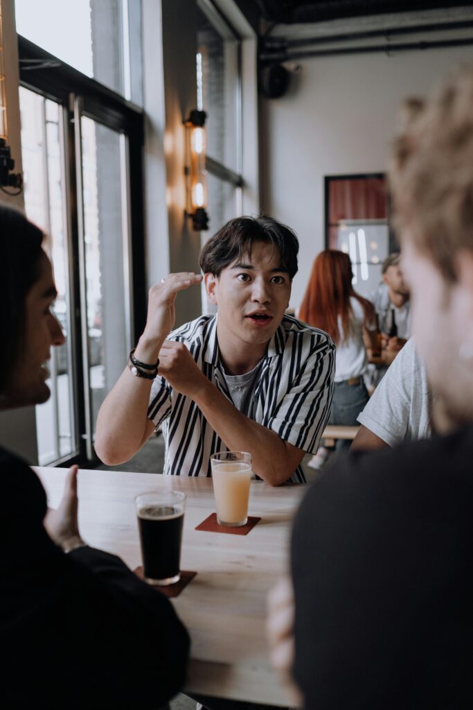 A group of friends enjoying drinks and a lively conversation at an indoor pub setting.